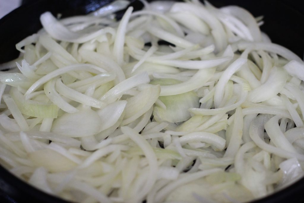 sliced white onions in pan