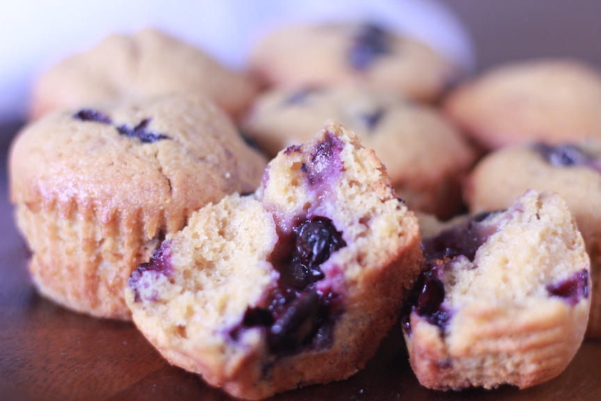 blueberry muffin in two halves with whole muffins in background