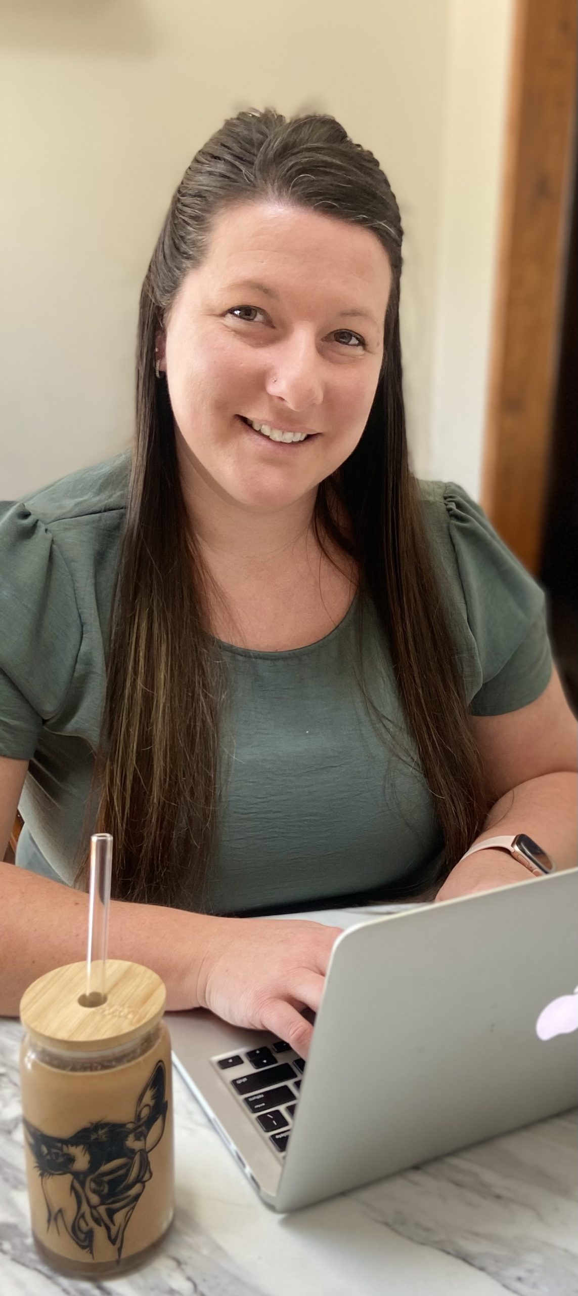 female sitting at computer typing with coffee in front of her